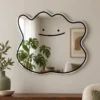 01-smile-mirror-main Smile blob acrylic wall mirror with a black smiling face and irregular outline on a warm neutral wall.